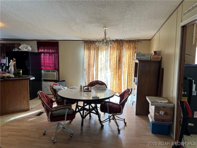 dining area with cooling unit, a textured ceiling, light hardwood / wood-style flooring, and a notable chandelier