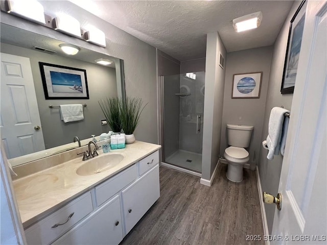 bathroom featuring hardwood / wood-style floors, vanity, walk in shower, toilet, and a textured ceiling