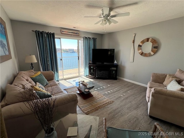 living room with hardwood / wood-style flooring, ceiling fan, and a textured ceiling