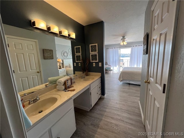 bathroom with vanity, hardwood / wood-style floors, a textured ceiling, and ceiling fan