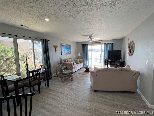 living room with ceiling fan, wood-type flooring, and a textured ceiling