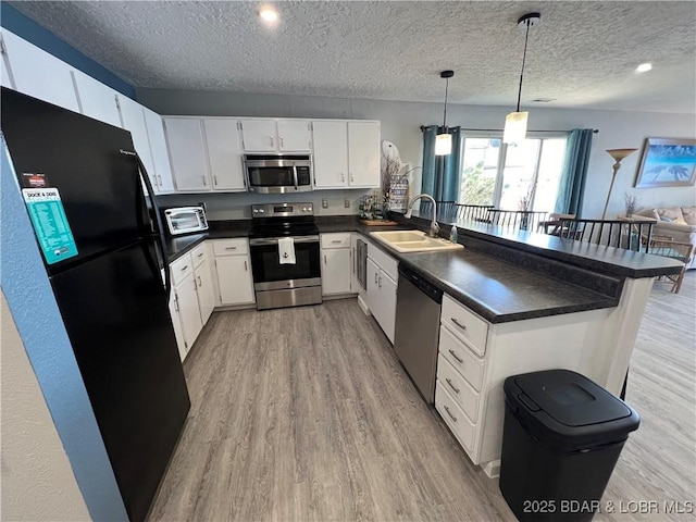 kitchen with white cabinetry, appliances with stainless steel finishes, decorative light fixtures, and sink