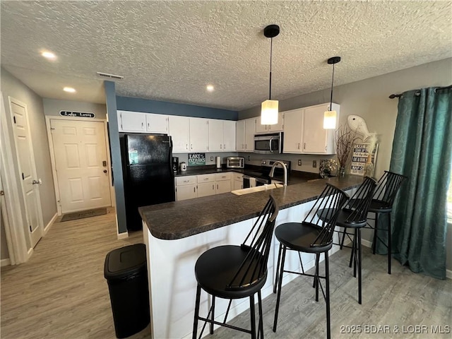 kitchen with black fridge, white cabinets, and a kitchen breakfast bar