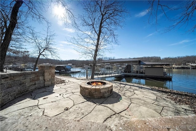 view of patio featuring a water view, a boat dock, and a fire pit