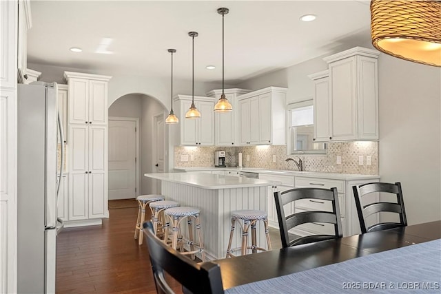 kitchen featuring stainless steel refrigerator, a center island, and white cabinets