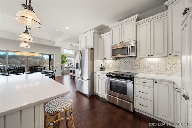 kitchen featuring pendant lighting, appliances with stainless steel finishes, dark hardwood / wood-style floors, white cabinets, and decorative backsplash