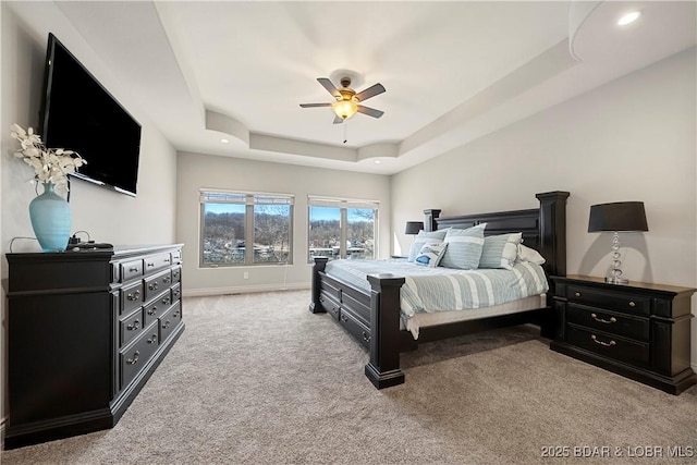 carpeted bedroom featuring ceiling fan and a tray ceiling