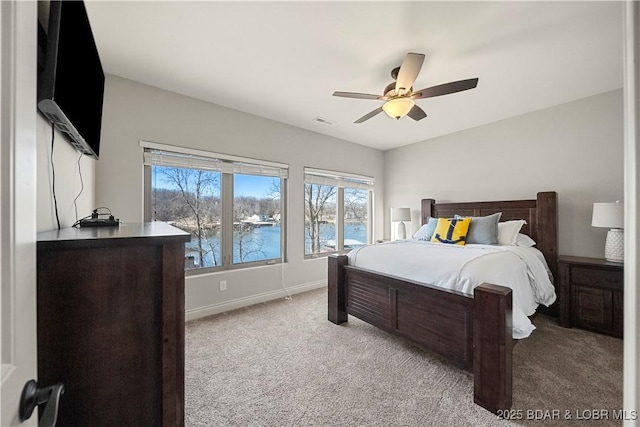 bedroom featuring a water view, light carpet, and ceiling fan