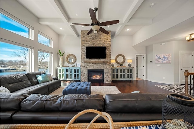 living room featuring beam ceiling, a high ceiling, coffered ceiling, dark hardwood / wood-style flooring, and a stone fireplace