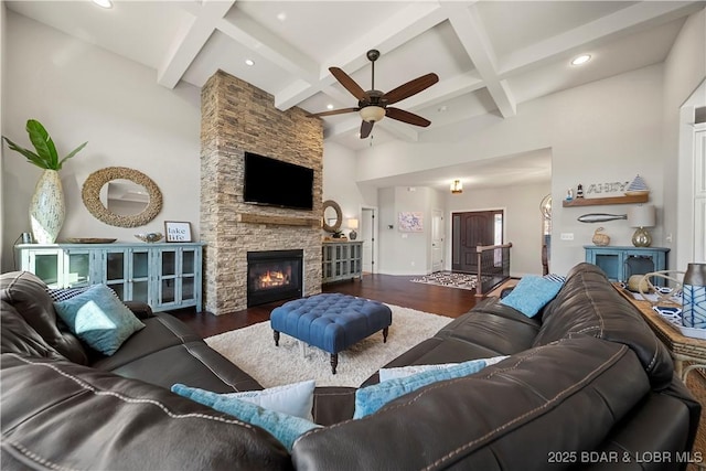 living room featuring a stone fireplace, dark hardwood / wood-style floors, beamed ceiling, and a high ceiling