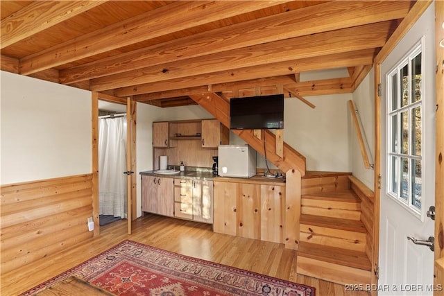 kitchen featuring wood ceiling, beam ceiling, sink, and light wood-type flooring