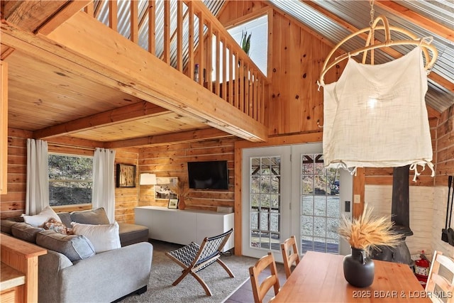 living room with beamed ceiling, carpet, a wealth of natural light, and wooden walls