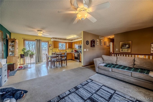 living room featuring ceiling fan, light carpet, and a textured ceiling