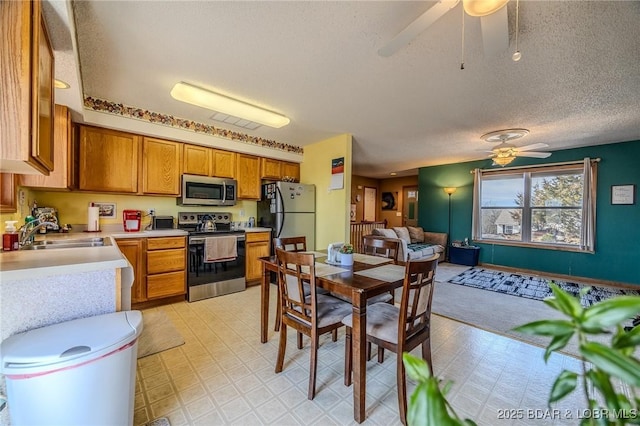 kitchen with appliances with stainless steel finishes, sink, a textured ceiling, and ceiling fan