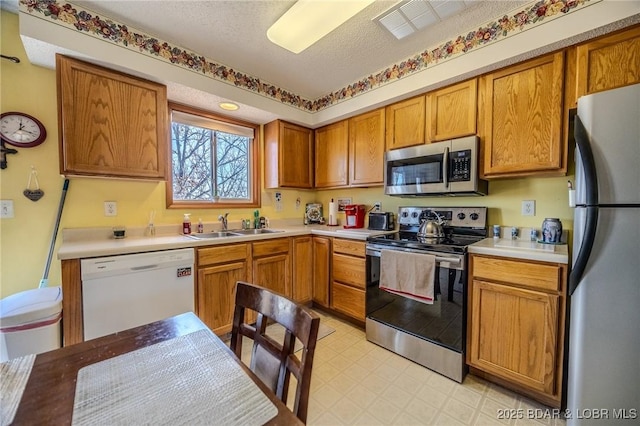 kitchen with sink, a textured ceiling, and appliances with stainless steel finishes