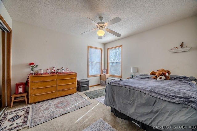 bedroom featuring ceiling fan, light colored carpet, a closet, and a textured ceiling