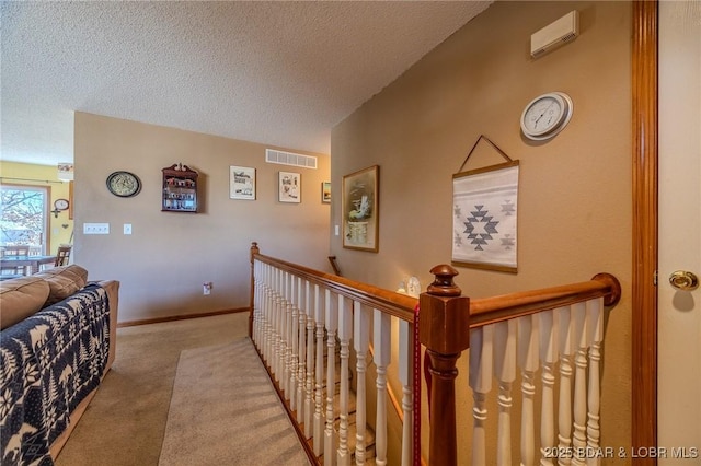 corridor featuring light carpet and a textured ceiling