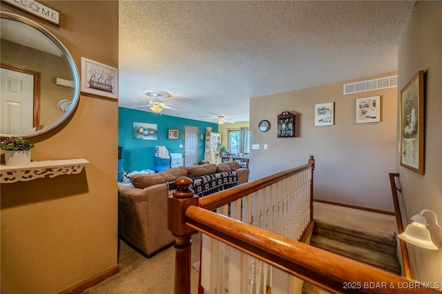 hallway with light colored carpet and a textured ceiling