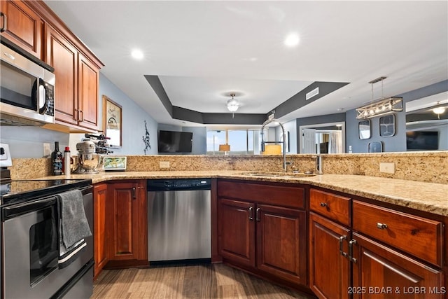 kitchen featuring light stone counters, sink, hanging light fixtures, and appliances with stainless steel finishes