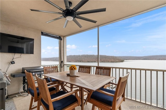 sunroom / solarium with ceiling fan and a water view