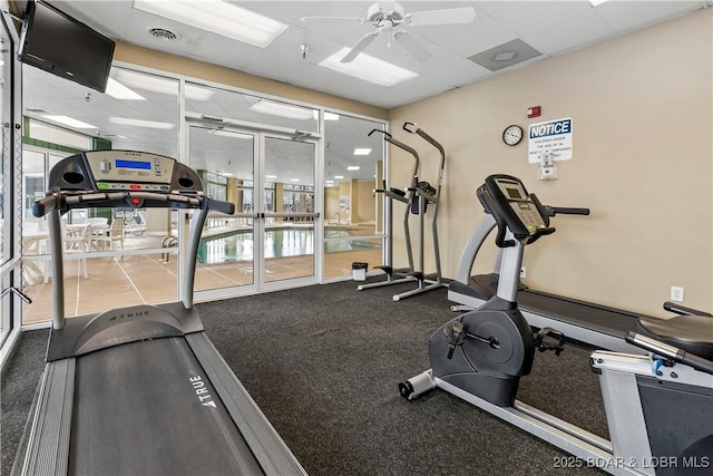 exercise room with a drop ceiling and ceiling fan