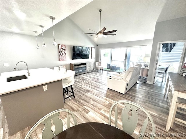 living room with sink, ceiling fan, hardwood / wood-style floors, high vaulted ceiling, and a textured ceiling