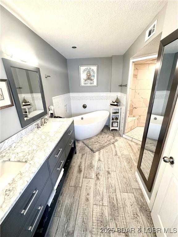 bathroom with wood-type flooring, a bathtub, vanity, and a textured ceiling