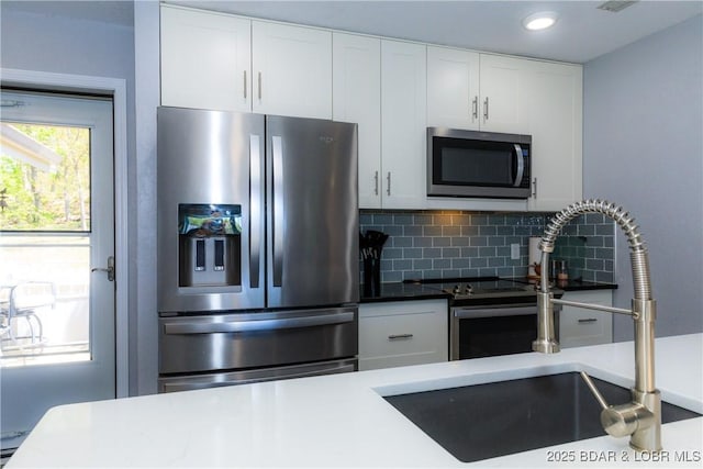 kitchen featuring white cabinetry, stainless steel appliances, sink, and backsplash