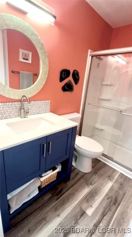 bathroom with tasteful backsplash, hardwood / wood-style flooring, vanity, an enclosed shower, and toilet