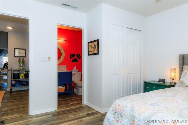 bedroom with hardwood / wood-style flooring, connected bathroom, and a closet