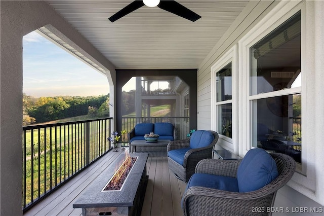 wooden deck with an outdoor living space with a fire pit and ceiling fan