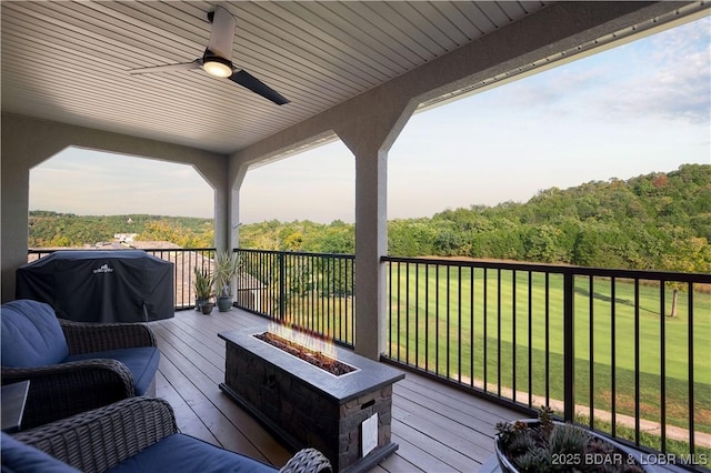 deck featuring grilling area, a yard, ceiling fan, and a fire pit