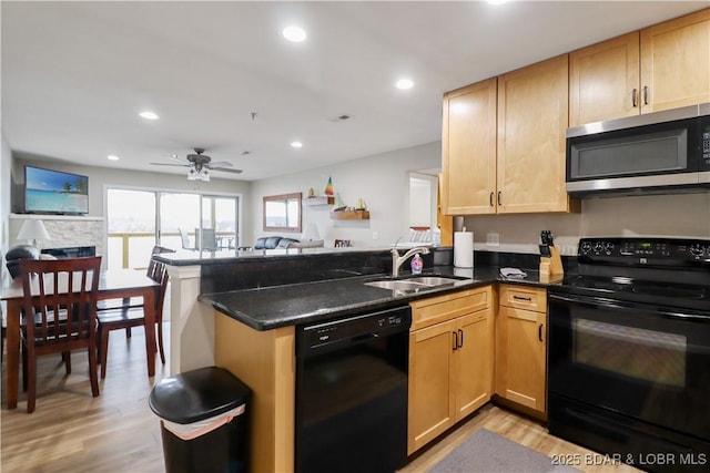 kitchen featuring dark stone counters, kitchen peninsula, sink, and black appliances