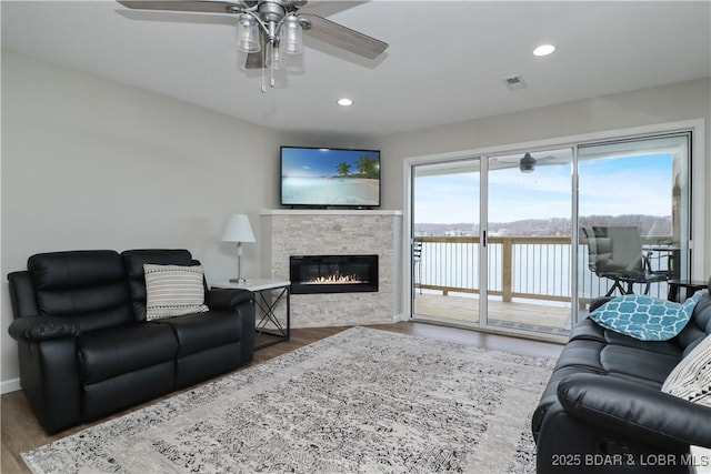 living room with hardwood / wood-style flooring, a fireplace, and ceiling fan