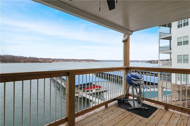 deck with ceiling fan and a water view