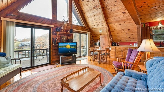 living room with vaulted ceiling with beams, wood ceiling, and light hardwood / wood-style floors