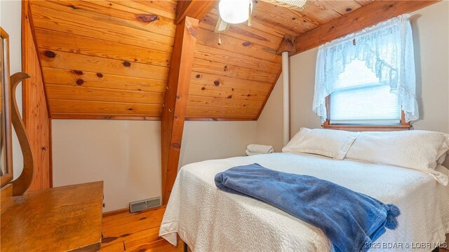 bedroom featuring vaulted ceiling with beams, wooden ceiling, and light wood-type flooring