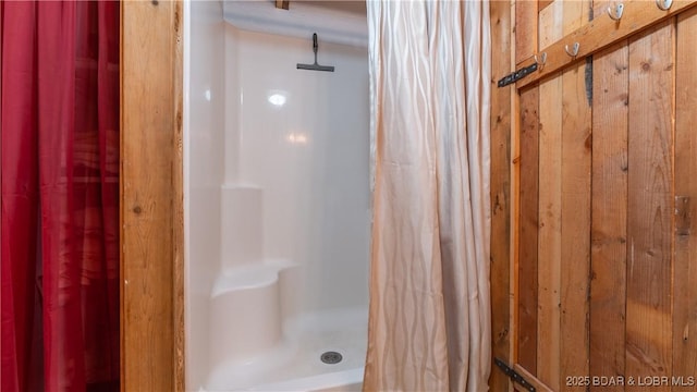 bathroom featuring a shower with curtain and wood walls