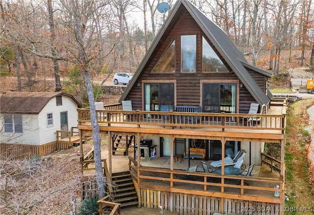 rear view of house with a wooden deck and a storage shed