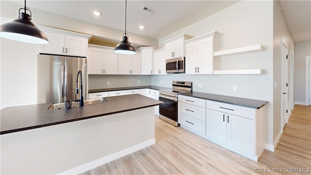 kitchen featuring pendant lighting, stainless steel appliances, light hardwood / wood-style floors, and white cabinets