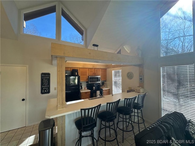 223 Waterscape Dr, Osage Beach, MO 65065 - kitchen featuring black appliances, high vaulted ceiling, brown cabinets, light countertops, and tile patterned floors