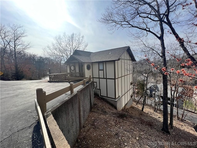 view of property exterior with fence and roof with shingles