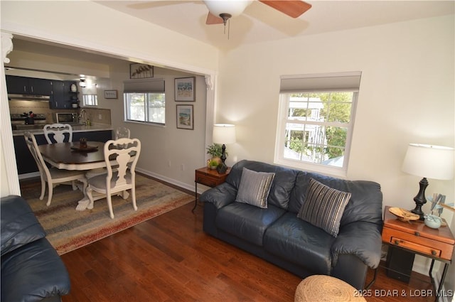 living room with ceiling fan, plenty of natural light, and dark hardwood / wood-style flooring