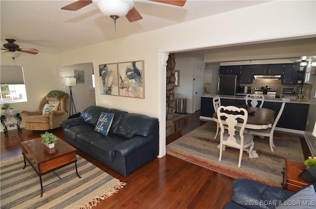 living room featuring dark wood-type flooring and ceiling fan