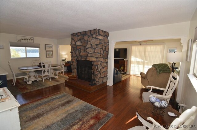 living room featuring dark wood-type flooring, a fireplace, and a textured ceiling