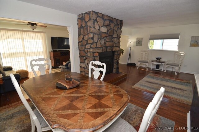 dining room with a fireplace, dark hardwood / wood-style floors, and ceiling fan