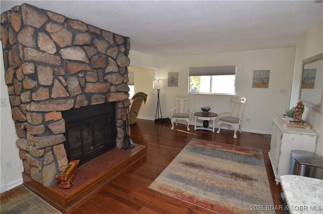 living room featuring dark hardwood / wood-style floors, a textured ceiling, and a fireplace