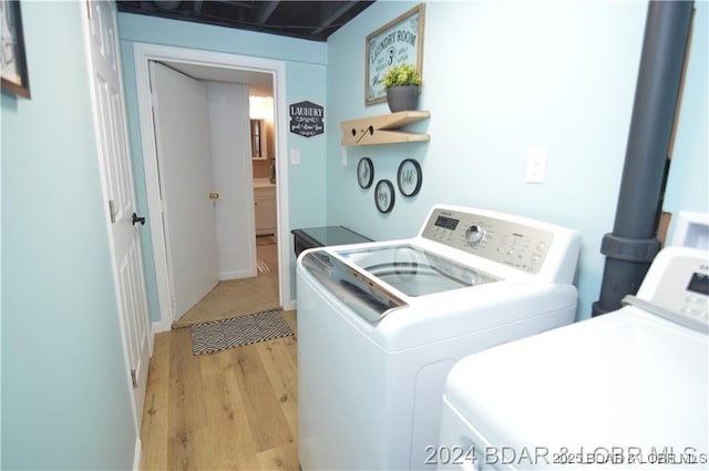 laundry area with light hardwood / wood-style floors and washer and dryer