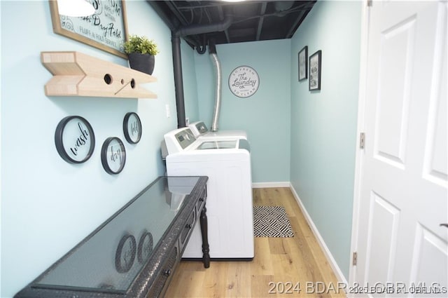 laundry room featuring washing machine and clothes dryer and light hardwood / wood-style floors