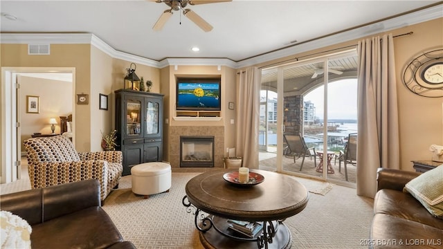 living room with crown molding, ceiling fan, a fireplace, and carpet flooring